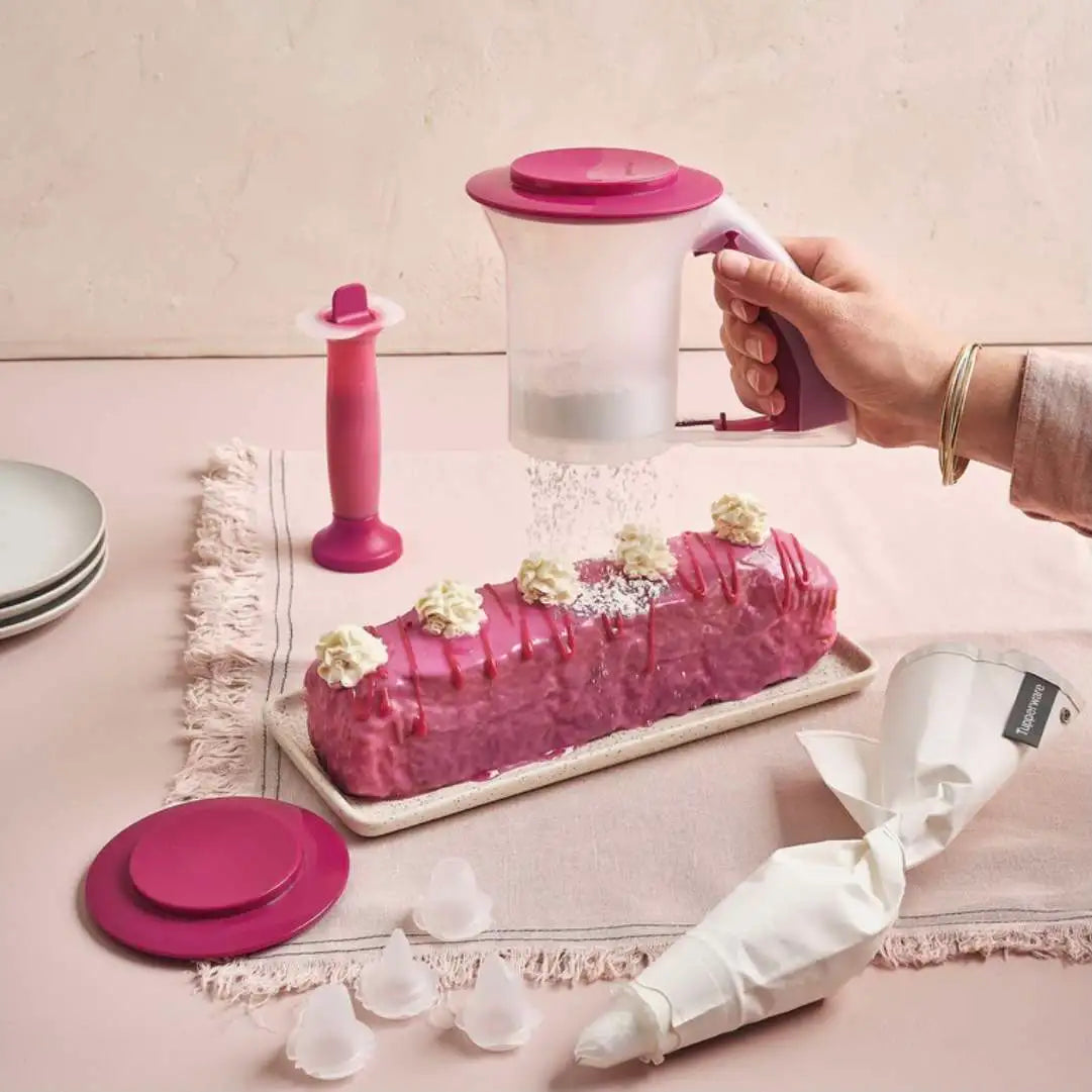 Tupperware powder sifter dusting powdered sugar over a pink glazed cake