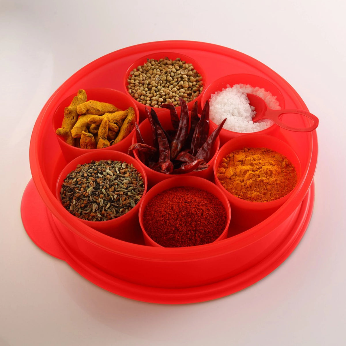 Red plastic spice box with seven compartments filled with assorted spices and salt