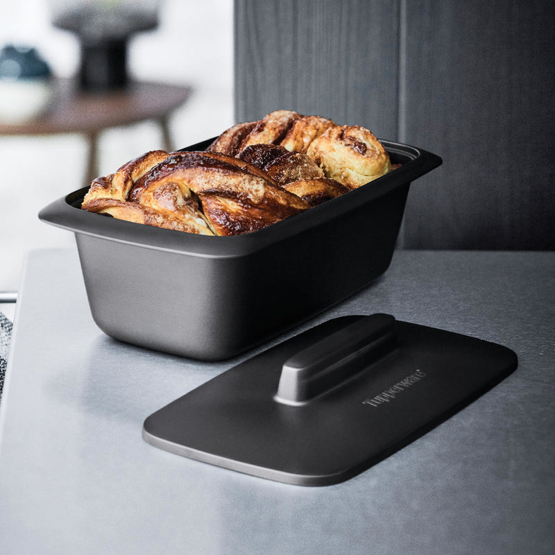 Tupperware UltraPro Terrine filled with golden brown cinnamon rolls and a matching black lid.