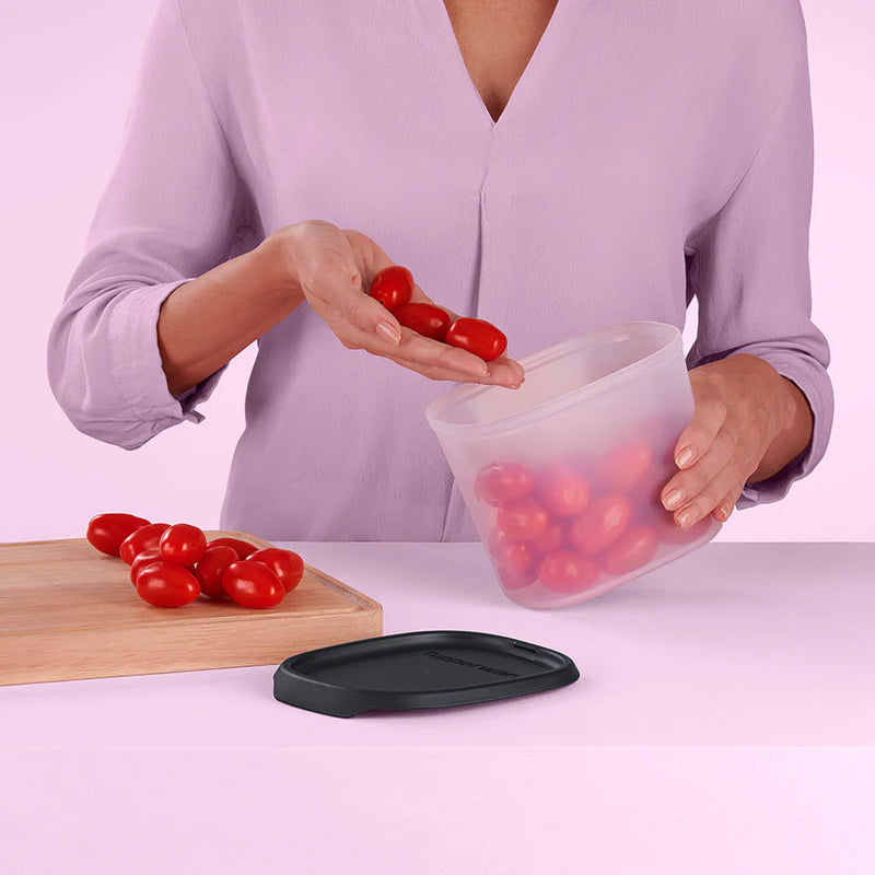 Vrouw gebruikt transparante opbergbox met zwarte deksel voor cherrytomaten in de keuken