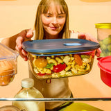 Woman holding a Tupperware Voilà rectangular glass container filled with pasta salad.